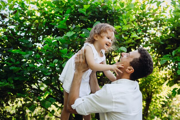 Cheerful child touches father's face while they pose in green forest 