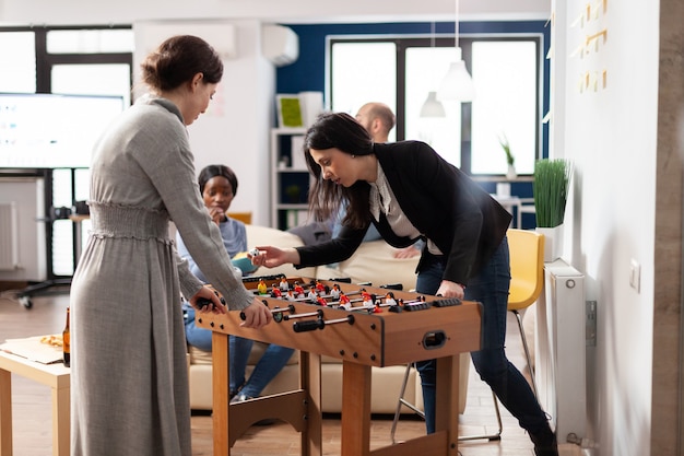 Cheerful colleagues enjoying game at foosball table