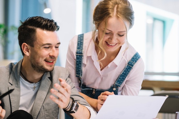 Cheerful colleagues looking at plans on paper