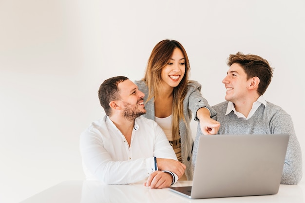 Free photo cheerful colleagues looking at project on laptop in office