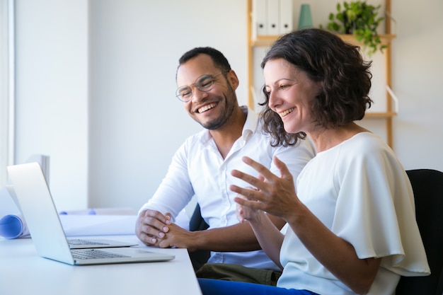 Free photo cheerful colleagues using laptop for video call