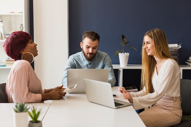 Cheerful colleagues using laptops