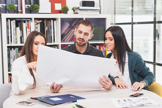 Free photo cheerful colleagues working on blueprint