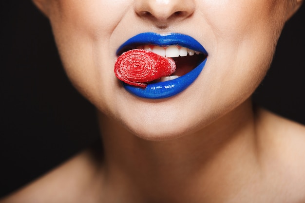  cheerful colorful lips holding sweeties with teeth.