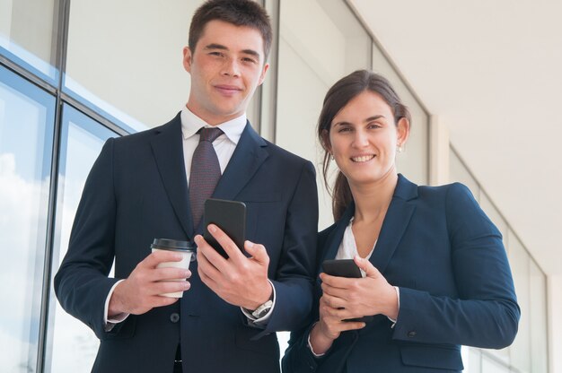 Cheerful confident businesspeople with smartphones