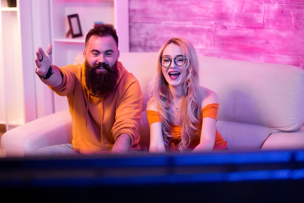 Cheerful couple after wining a ccompetition of online video games. Couple playing games home. Neon light.