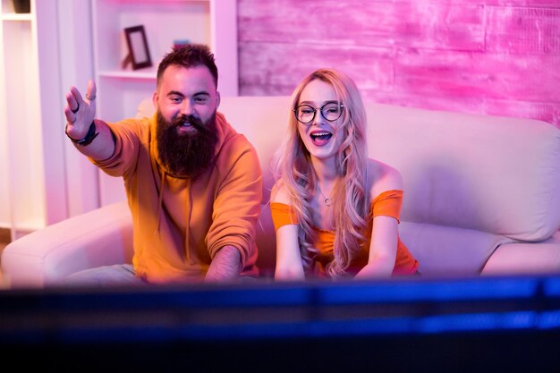 Cheerful couple after wining a ccompetition of online video games. Couple playing games home. Neon light.