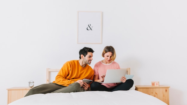 Free photo cheerful couple browsing laptop on bed