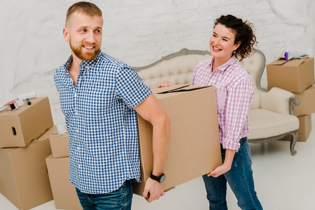 Cheerful couple carrying big box