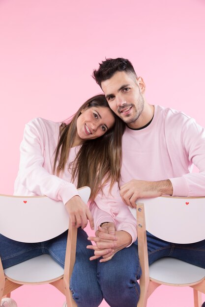 Cheerful couple on chairs holding hands 