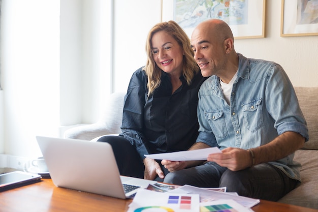 Cheerful couple of clients consulting interior designer