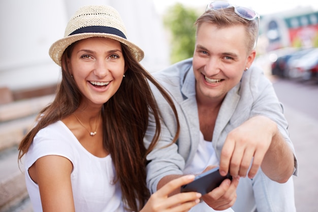 Cheerful couple having fun playing with smartphone