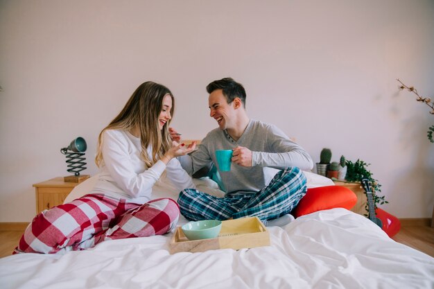 Cheerful couple having nice breakfast in bed