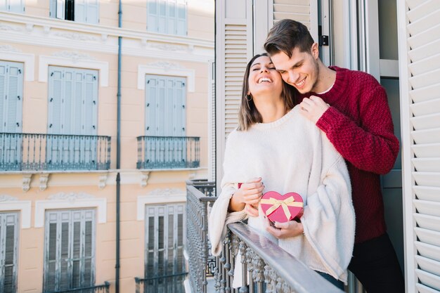 Cheerful couple hugging on balcony