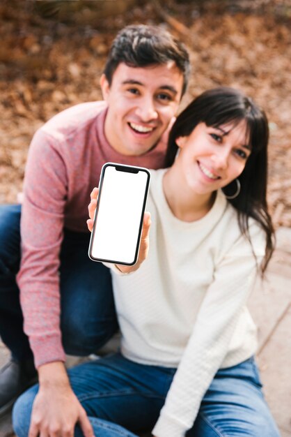 Cheerful couple hugging showing smartphone screen
