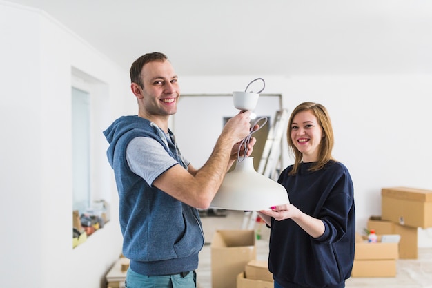 Free photo cheerful couple installing lamp