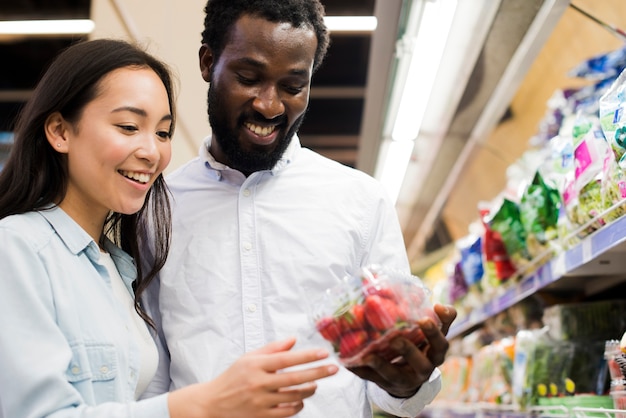 Cheerful couple picking strawberry in grocery store