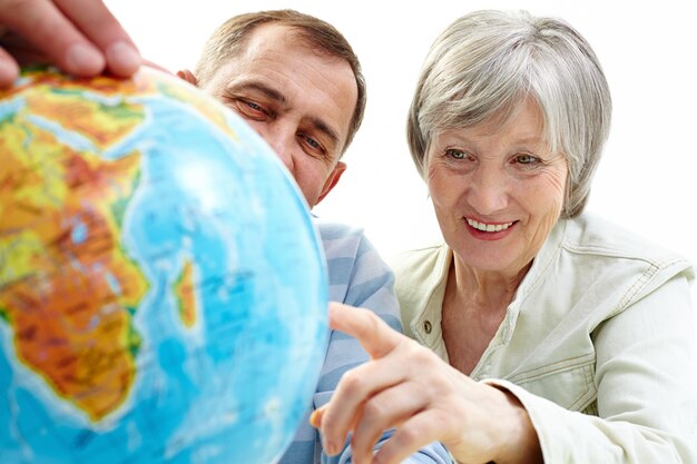 Cheerful couple pointing at globe
