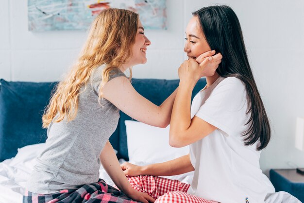 Foto gratuita coppie allegre che si siedono a letto e fronte commovente