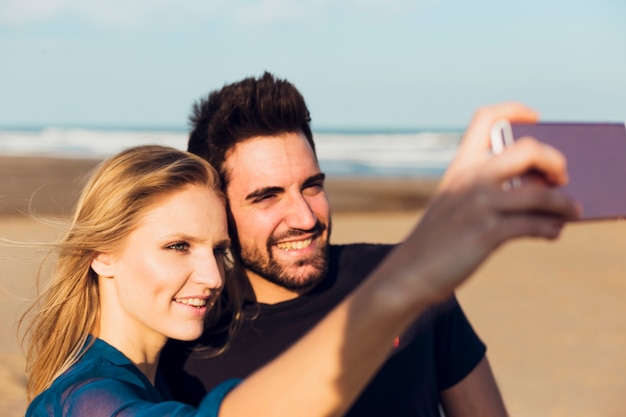 Cheerful couple taking selfie on beach