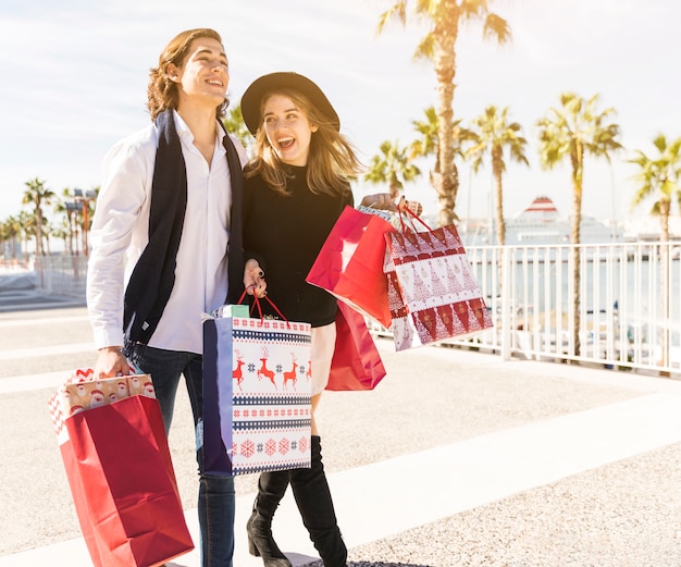 Cheerful couple walking with Christmas shopping bags