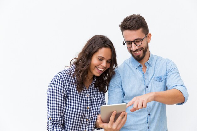 Cheerful couple watching content on tablet and laughing