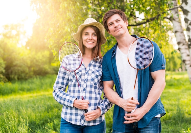 Cheerful couple with badminton rackets in park