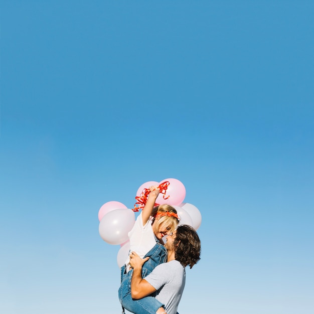 Cheerful couple with balloons cuddling