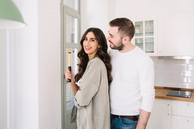 Cheerful couple with hammer at wall