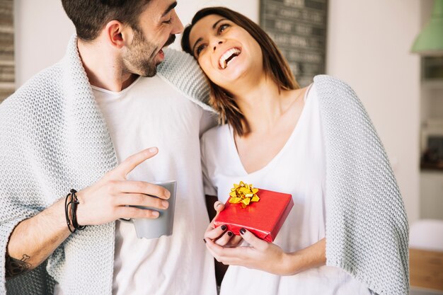 Cheerful couple with present and mug