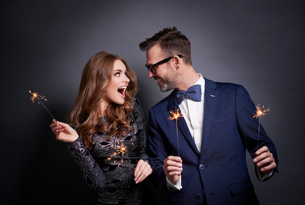 Cheerful couple with sparkler flirting