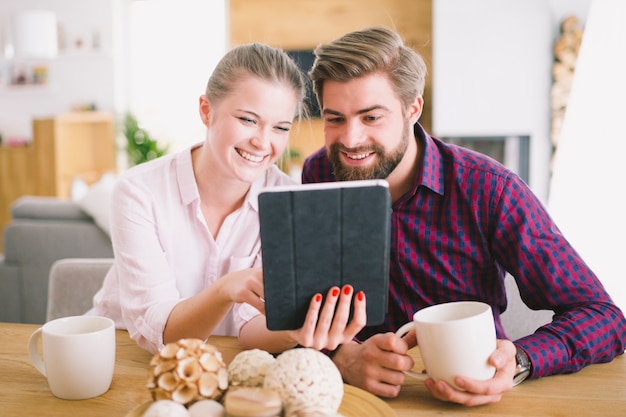 Cheerful couple with tablet at desk
