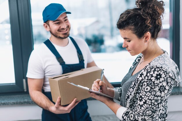 Cheerful courier near signing woman