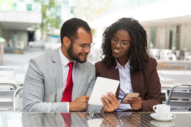 Cheerful coworkers looking at each other gadgets screen