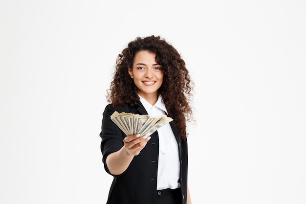Free photo cheerful curly business girl holding money