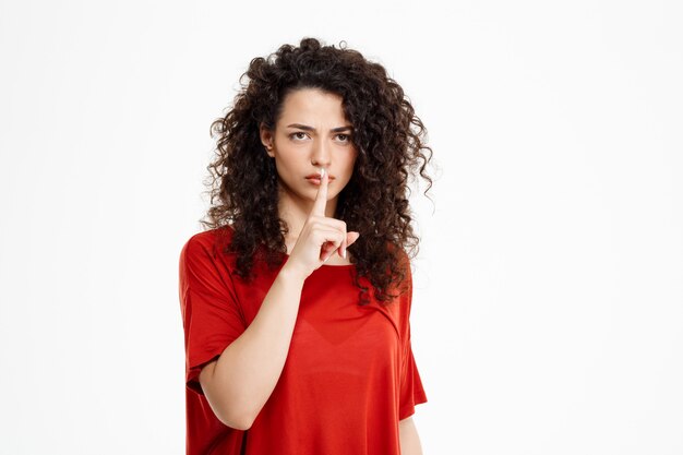  cheerful curly girl make silence gesture