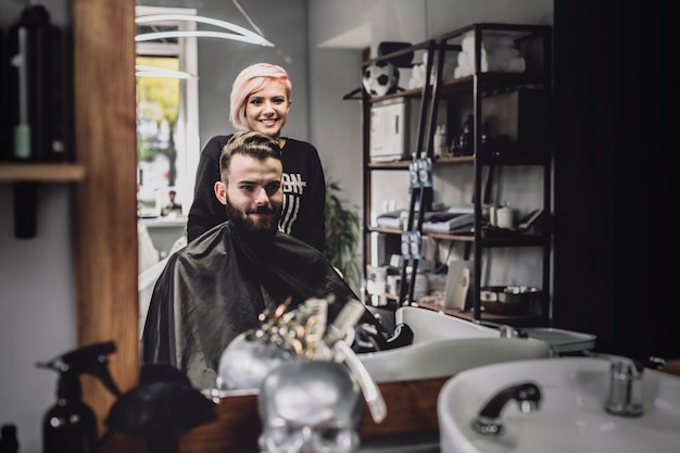 Cheerful customer and barber in shop