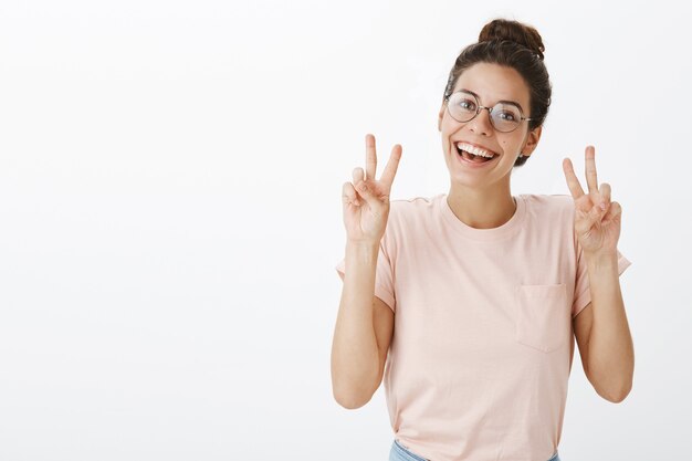 Cheerful cute girl with glasses posing against the white wall