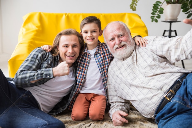 Cheerful cute son hugging dad and grandfather
