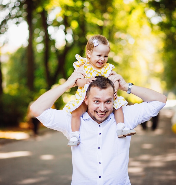 Cheerful dad holds his daughter on the neck 