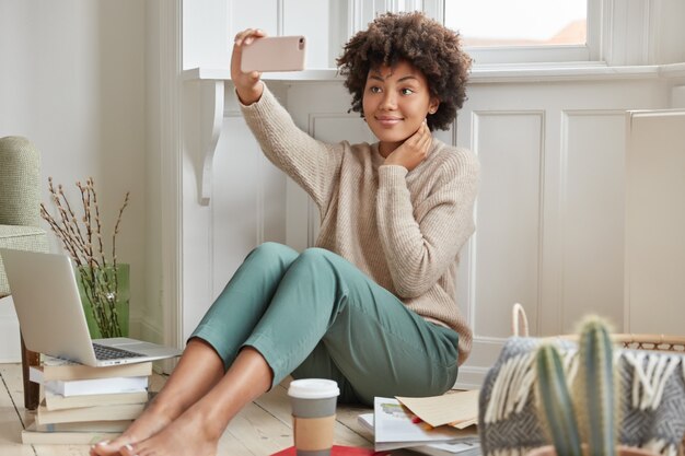 Cheerful dark skinned girl wears warm sweater and fashionable trousers