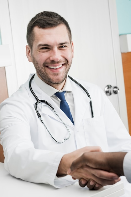 Cheerful doctor shaking hand of colleague