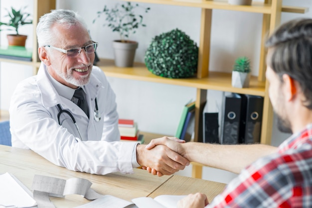 Cheerful doctor shaking hand of patient