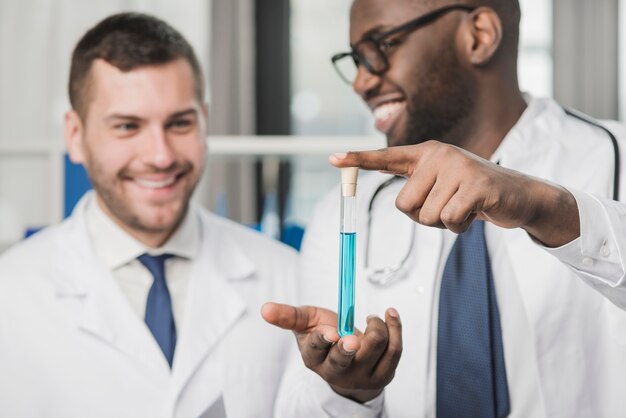 Cheerful doctors holding test tube