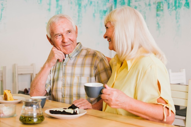 Веселая пожилая пара пьет чай и разговаривает