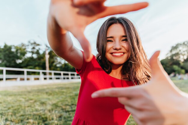 Cheerful emotional woman posing in park.  girl with dark shiny hair having fun outdoor.