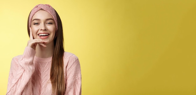 陽気で楽な若い魅力的なヨーロッパ人女性 編み物のピンクのヘッドバンドのセーターで に触れる