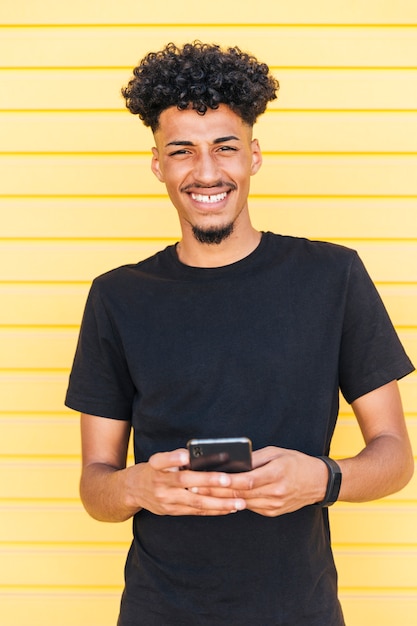 Cheerful ethnic man using phone