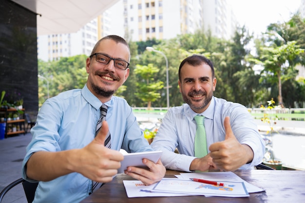 Cheerful excited businessmen showing thumbs-up