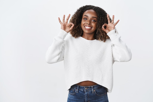 Free photo cheerful excited darkskinned friendly young woman smiling broadly show okay ok approval gesture like awesome product recommend give no problem sign agree terms satisfied tryingout service